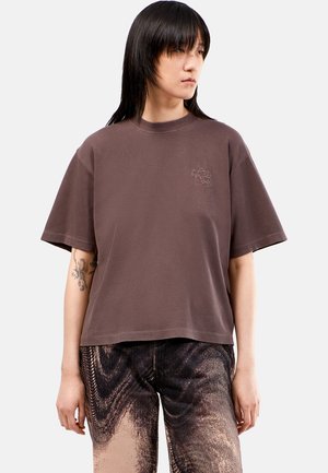 T-shirt court marron à manches courtes, col rond, avec un logo brodé sur la poitrine gauche. Tissu en coton doux avec une coupe décontractée.