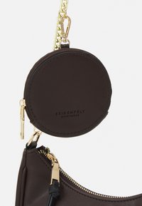 Porte-monnaie rond en cuir marron foncé avec fermeture éclair et chaîne dorée, attaché à un sac en cuir marron foncé assorti avec fermeture éclair dorée.