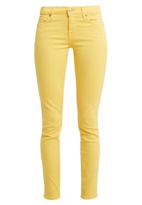 Jeans amarillos ajustados con una textura suave, que cuentan con un cierre de botón en la parte frontal y bolsillos, diseñados para un ajuste ceñido a lo largo de las piernas.