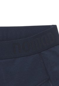 Marineblaue Sportshorts mit einem strukturierten elastischen Bund, der den eingeprägten schwarzen Schriftzug "nomad" trägt. Glatter Stoff und stabile Nähte.