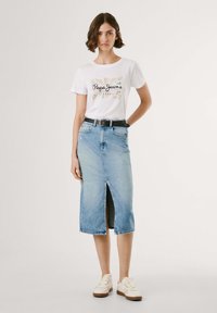 Vit t-shirt med "Pepe Jeans London" tryck, ihopparad med en ljusblå denimkjol med en framficka, kompletterad med ett svart bälte och ljusa skor.