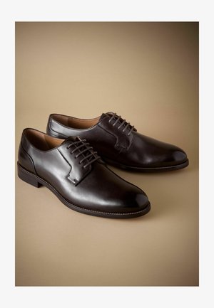 Ruske nahkakengät, joissa on sileä pinta. Varustettu nauhaketjulla, pyöreällä kärjellä ja ommellulla yksityiskohdalla pohjan ympärillä.