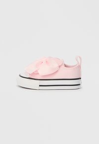 Růžové plátěné tenisky s velkou saténovou mašlí na přední straně, bílým gumovým špičákem a černým pruhovaným podešví. Obsahují poutko na zadní straně.