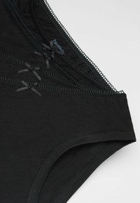 Czarne bawełniane majtki o gładkiej fakturze, z ozdobnym koronkowym wykończeniem i małymi czarnymi kokardkami z przodu. Klasyczny design bielizny.