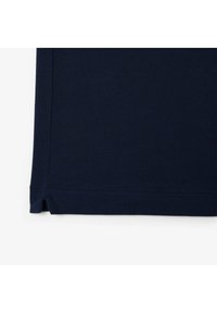 Námořnicky modré tričko s texturovanou látkou a bočními rozparky na spodním lemu. Design je jednoduchý s klasickým střihem a dokončenými okraji.