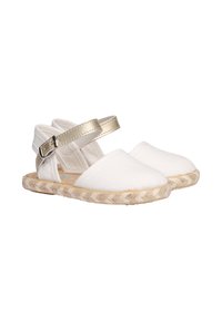 Zapatos espadrilles de lienzo blanco con una correa metálica dorada en el tobillo y suela de yute trenzado, con punta redonda y diseño de espalda abierta.