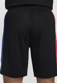 Sorte sportshorts lavet af tekstureret stof, med blå og røde sidelister, elastisk talje og en afslappet pasform.
