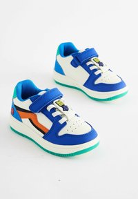 Baskets bleues et blanches avec une sangle velcro, des accents noirs et orange, une semelle en caoutchouc et une partie supérieure texturée avec des perforations.