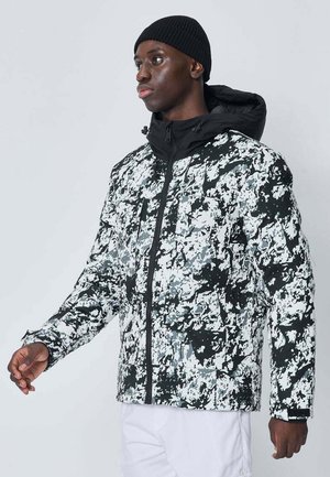 Veste de camouflage noire et blanche avec capuche, fermeture éclair et finition texturée. Présente des poches accentuées et un design rembourré.