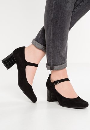 Sorte ruskinds højhælede sko med rund tå, ankelrem og struktureret krokodillemønster på blokhælen. Båret med opsmøgte jeans.