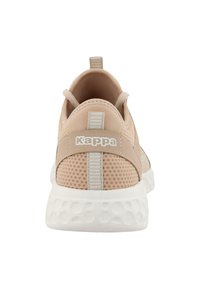 Chaussure de sport beige clair avec tige en tissu en maille, un logo blanc, un dos texturé et une semelle en caoutchouc blanche épaisse avec des découpes circulaires.
