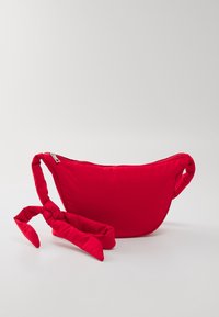Borsa a spalla rossa in nylon con forma curva, chiusura con zip e tracolla annodata per trasporto regolabile. Texture liscia senza motivi.