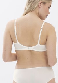 Soutien-gorge léger de couleur crème avec des bretelles réglables et une fermeture à crochet. Texture lisse et design minimaliste, mettant en valeur une silhouette subtile.