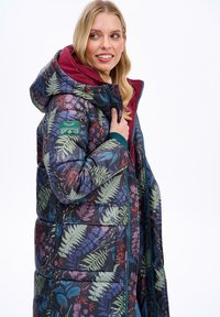 Květinová péřová bunda v tmavých tónech, zdobená vzory zelených a fialových listů, s vínovým podšívkou kapuce a zipem po celé délce se bočními kapsami.