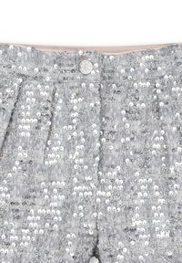 Shorts en sequins argentés avec un tissu texturé, dotés d'une fermeture à boutons et de plis. La surface reflète la lumière, créant un effet scintillant.
