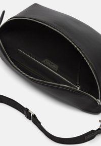 Sac en cuir noir avec un intérieur spacieux. Doté d'une fermeture éclair en métal argenté, d'une poche intérieure et d'une bandoulière ajustable pour plus de polyvalence. Texture lisse.