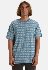 Short-sleeve t-shirt in light blue with a white leaf and diamond pattern. Crew neck design, soft fabric, relaxed fit.