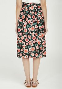 Gonna midi floreale con sfondo nero, caratterizzata da fiori rosa e bianchi, vita elasticizzata e tessuto fluido, abbinata a sandali leggeri.