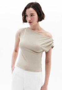 Beige, tætsiddende bluse med en off-shoulder design, korte ærmer og plisserede detaljer på skulderen. Glat stofkvalitet.