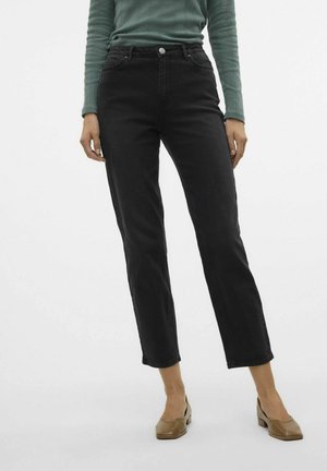 Jeans neri a gamba dritta con vita alta, cinque tasche e chiusura con bottone metallico. Indossati con un top verde a coste a maniche lunghe e scarpe marroni.