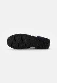 Black rubber outsole with deep, angled tread for traction. Reinforced heel and side accents in lighter colors. Durable material construction.