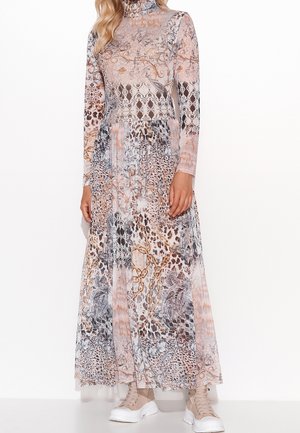 Femme portant une robe longue à manches longues et col montant avec un imprimé animalier et floral mélangé, associée à des baskets beige épaisses.