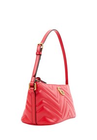 Sac à main en cuir rouge avec surpiqûres chevron, sangle à boucle dorée et logo G entrelacé doré sur le côté, vue inclinée sur fond blanc.