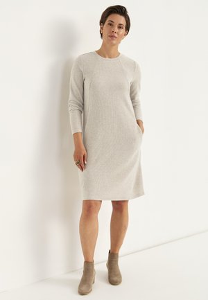 Ljusgrå tröjklänning med långa ärmar, ribbad struktur, rund halsringning, sidofickor och knälängd passform, kombinerad med beigea ankelboots.