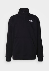 Felpa nera con colletto alto, zip a metà, tasca frontale e logo The North Face in bianco sulla parte sinistra del petto.