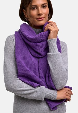 Sciarpa rosa a maglia sovrapposta a un maglione grigio chiaro, con una texture a coste e un tessuto morbido. La sciarpa si adagia elegantemente attorno al collo.