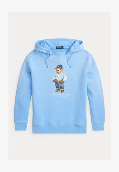 Svijetloplavi hoodie s medvjedićem koji nosi plavu kapu, traper košulju, rukavice, traperice i čizme, s natpisom "Polo Bear by Ralph Lauren" ispod.