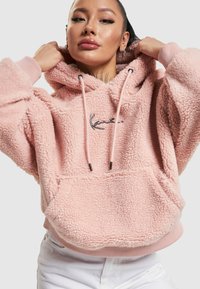 Roze fleece hoodie met een gestructureerde afwerking, trekkoordcapuchon en geborduurd logo. Heeft ribgebreide manchetten en een voorzak.