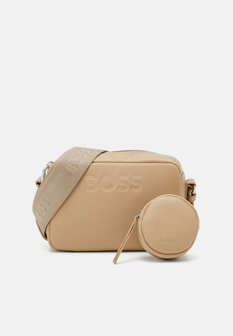 Beige läderaxelväska med en texturerad yta, med präglad branding, en avtagbar rund myntplånbok och en tygrem.