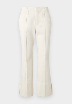Spodnie szyte na miarę w kremowym kolorze z przednimi zakładkami, szlufkami na pasek i subtelnymi rozcięciami przy szerokich mankietach nogawek.