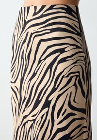 Gonna beige con motivo a strisce zebra nere, realizzata in tessuto morbido, con una forma aderente e un design a vita alta.