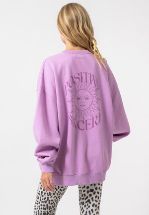 Bordo per dideli dydis megztinis su saulės grafika ir užrašu "TEIGIAMAI NORMATYVUS", derinamas su pilkų leopardų raštais leggingais. Minkšta texture.