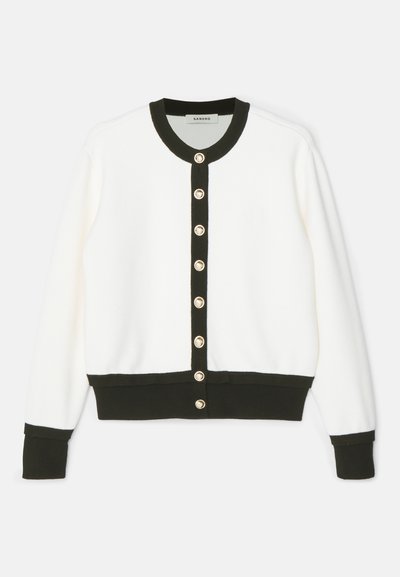 Gilet blanc avec bord noir sur le col, les poignets, la ligne de boutons et l'ourlet, comportant huit boutons dorés sur le devant.