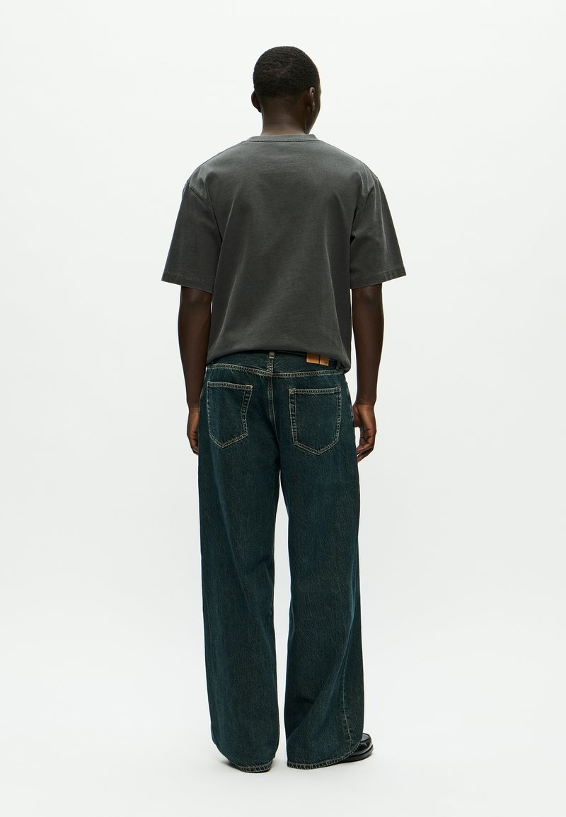 Gray short-sleeve t-shirt and wide-leg, dark blue denim jeans. Notable details include a visible waistband tab and slight texture variations.