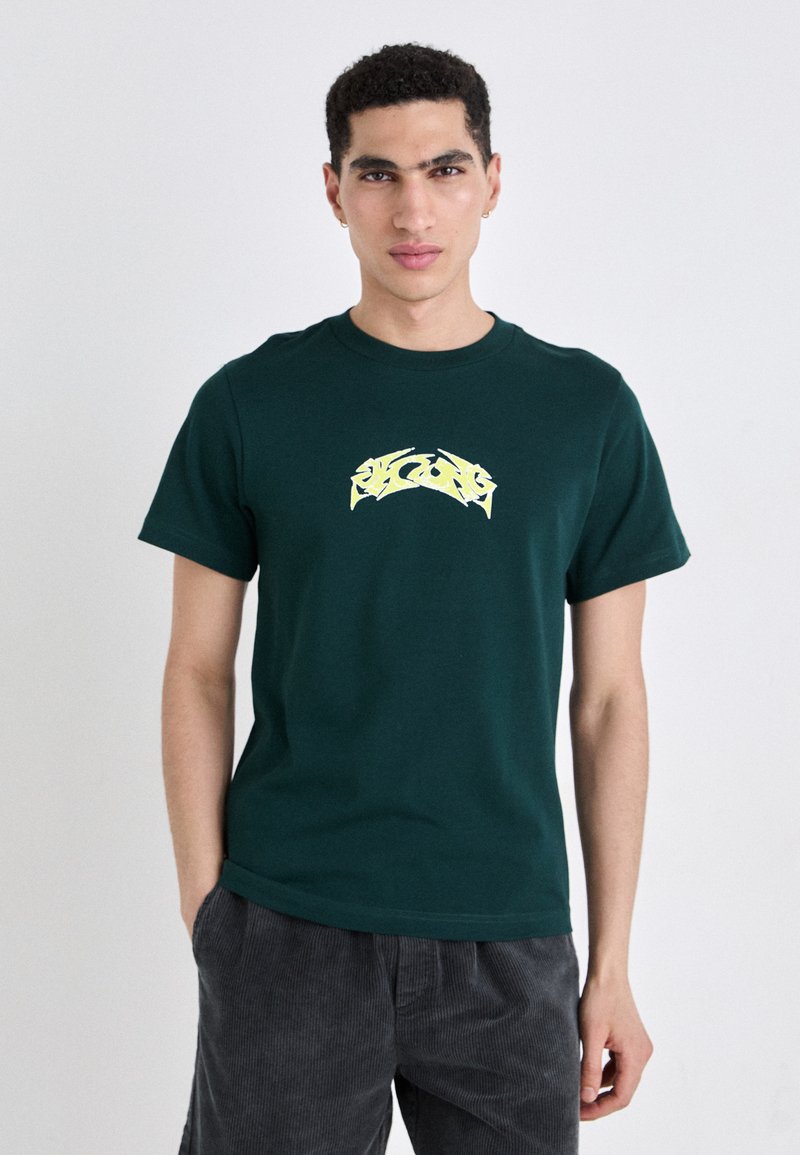Dark green t-shirt made of cotton, featuring a yellow graphic design at the chest. Short sleeves and a classic crew neckline.