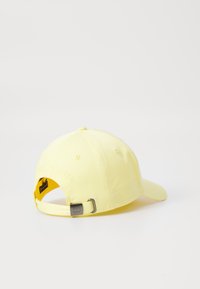 Casquette en coton jaune avec une visière courbée, sangle arrière ajustable et logo de la marque en relief à l'arrière. Texture douce et finition lisse.