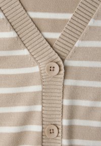 Cardigan beige et blanc à rayures, avec un col en V, des poignets côtelés, et une seule fermeture à bouton rond à l'avant. Texture en maille lisse.