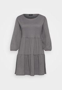 Grå långärmad, lager-på-lager mini-klänning med rund halsringning och strukturerad tyg, uppställd mot en platt vit bakgrund.