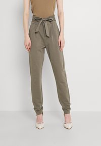 Olive green jogger pants with a high waist, tied belt, side pockets, and tapered cuffs, made from soft, stretchy fabric.