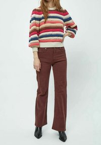 Knit sweater with multicolored horizontal stripes, ribbed cuffs and hem. Brown flared pants with front pockets and a smooth texture, paired with black ankle boots.