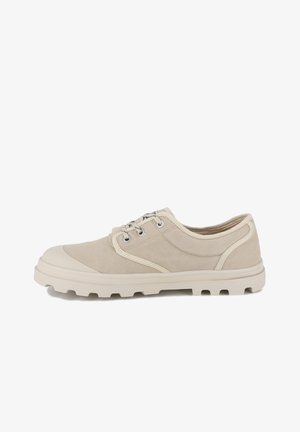 Beige canvas sneaker met rubberen neuskap en dikke witte zool. Voorzien van metalen oogjes en contrasterende stiksels, ontworpen voor casual gebruik.