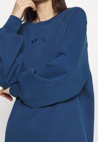 Blaues Baumwoll-Sweatshirt mit übergroßen Ärmeln und Rundhalsausschnitt. Mit gesticktem "Levi's"-Logo in dunklerem Blau auf der Brust.