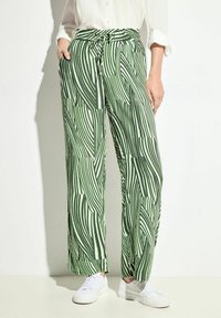 Gröna och vita mönstrade vida byxor med dragsko i midjan, med en strukturerad yta och sidofickor. Bärs med vita sneakers.