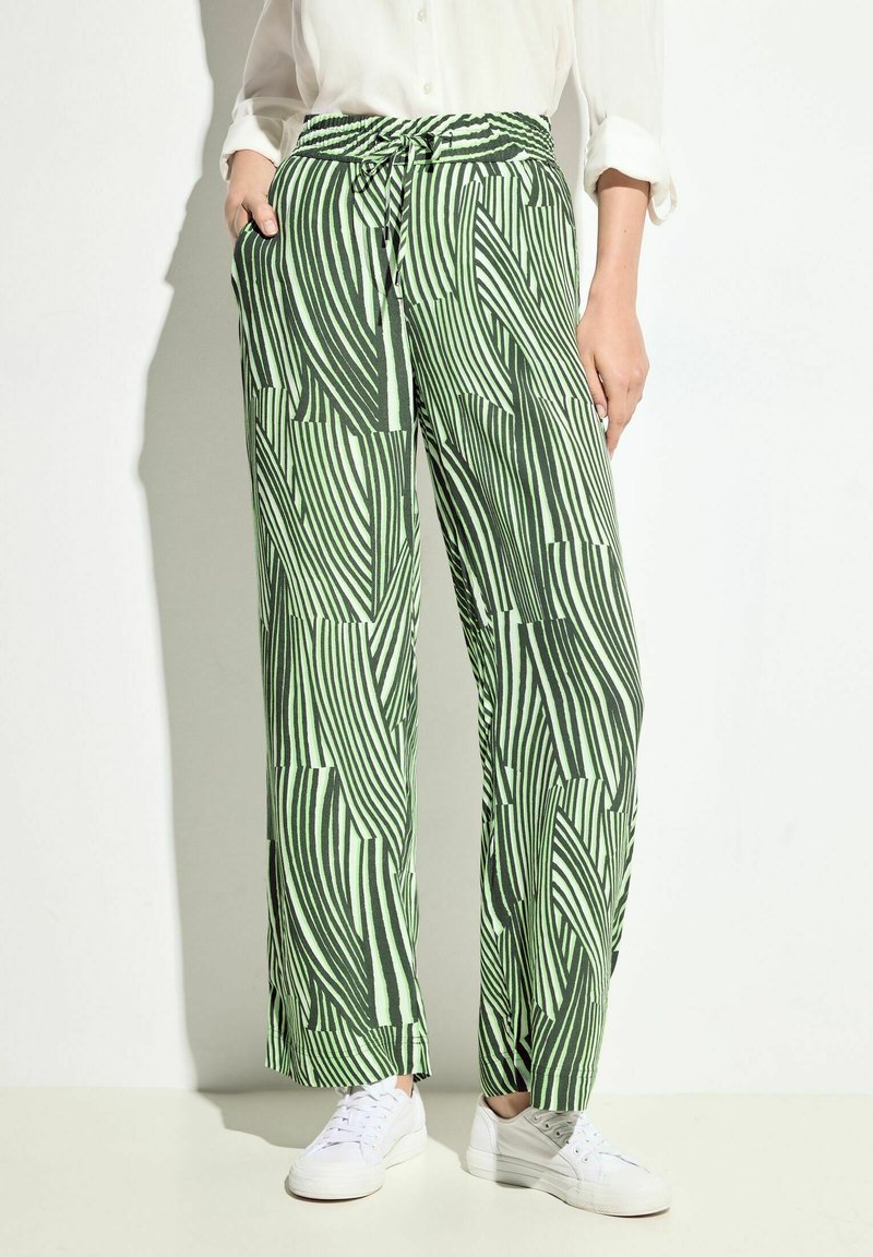 Gröna och vita mönstrade vida byxor med dragsko i midjan, med en strukturerad yta och sidofickor. Bärs med vita sneakers.