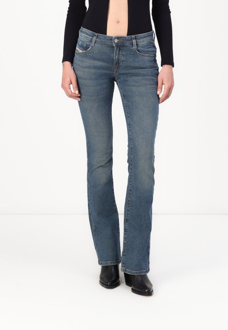 Vaqueros de denim azul deslavado con diseño de pernera acampanada, cintura a media altura y estilo de cinco bolsillos. Costuras detalladas y cierre de botón en la parte delantera.