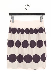 Une jupe courte en tissu beige clair, ornée de grands cercles violet foncé disposés en motif. Elle possède une ceinture unie et est suspendue à un cintre.